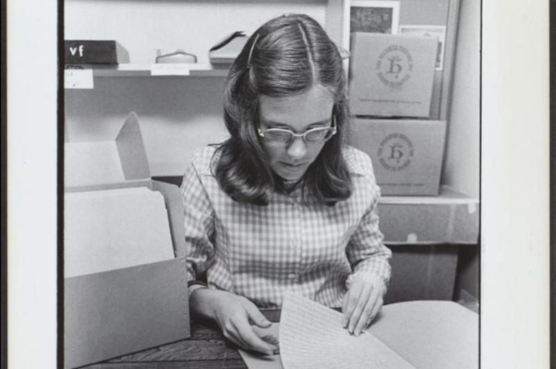 black and white photograph of a young woman sifting through an archival file